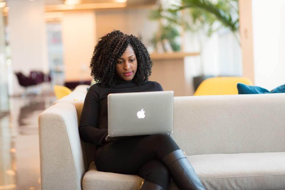 woman sitting on couch using laptop